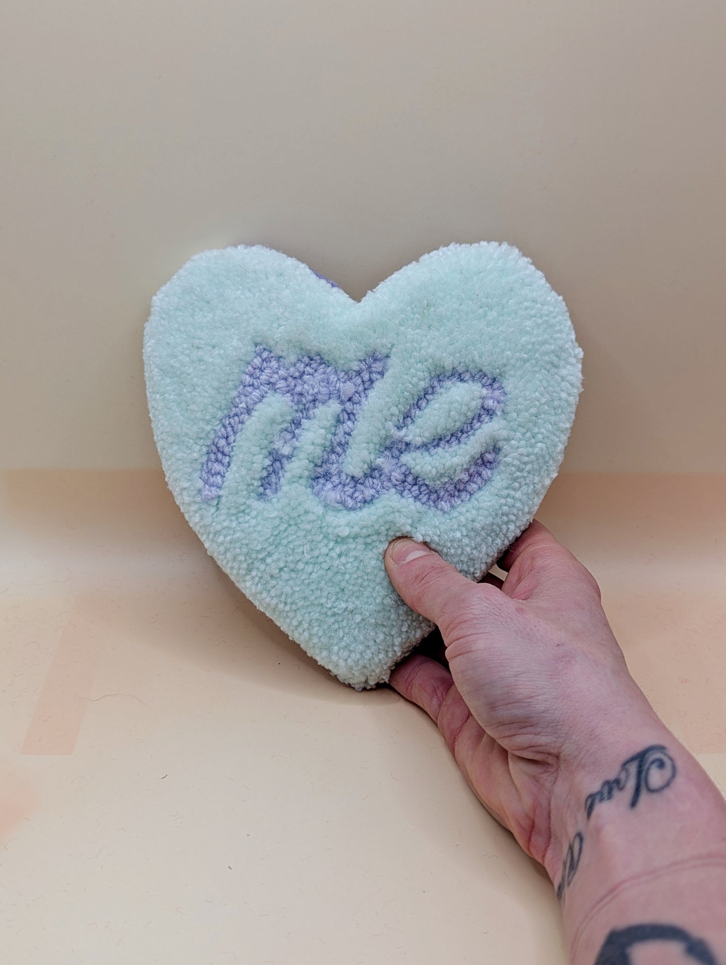 Soft tufted green and purple heart shaped mini rug/coaster with self love slogan