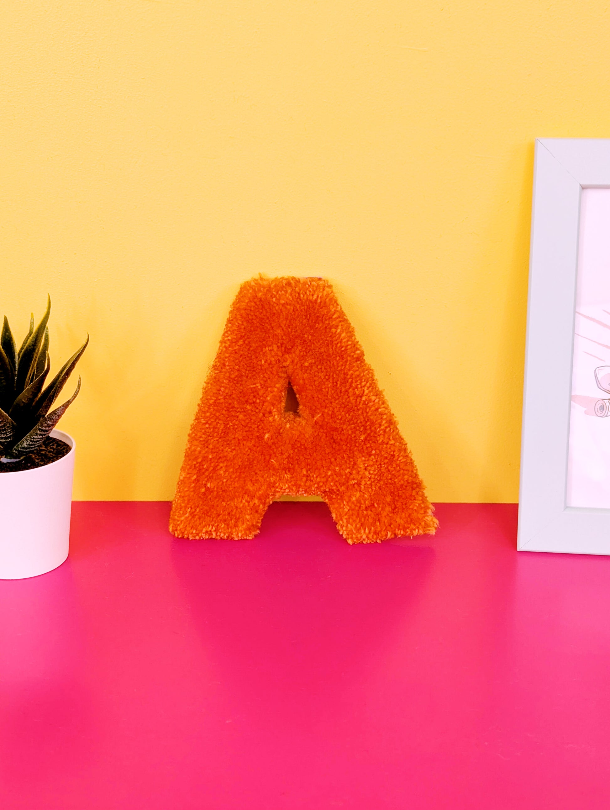 Soft tufted orange letter A with metal hook for easy hanging