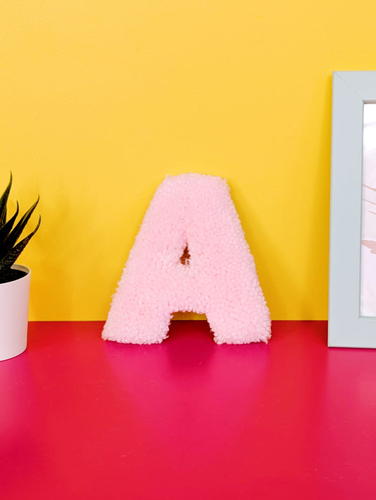 Soft tufted pink letter A with metal hook for easy hanging