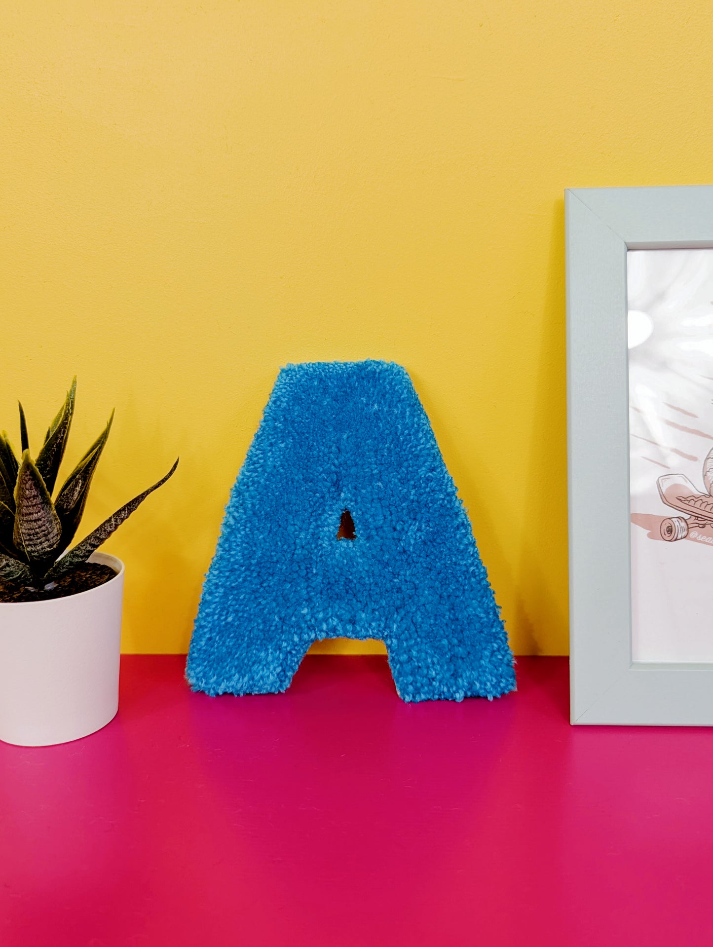 Soft tufted blue letter A with metal hook for easy hanging