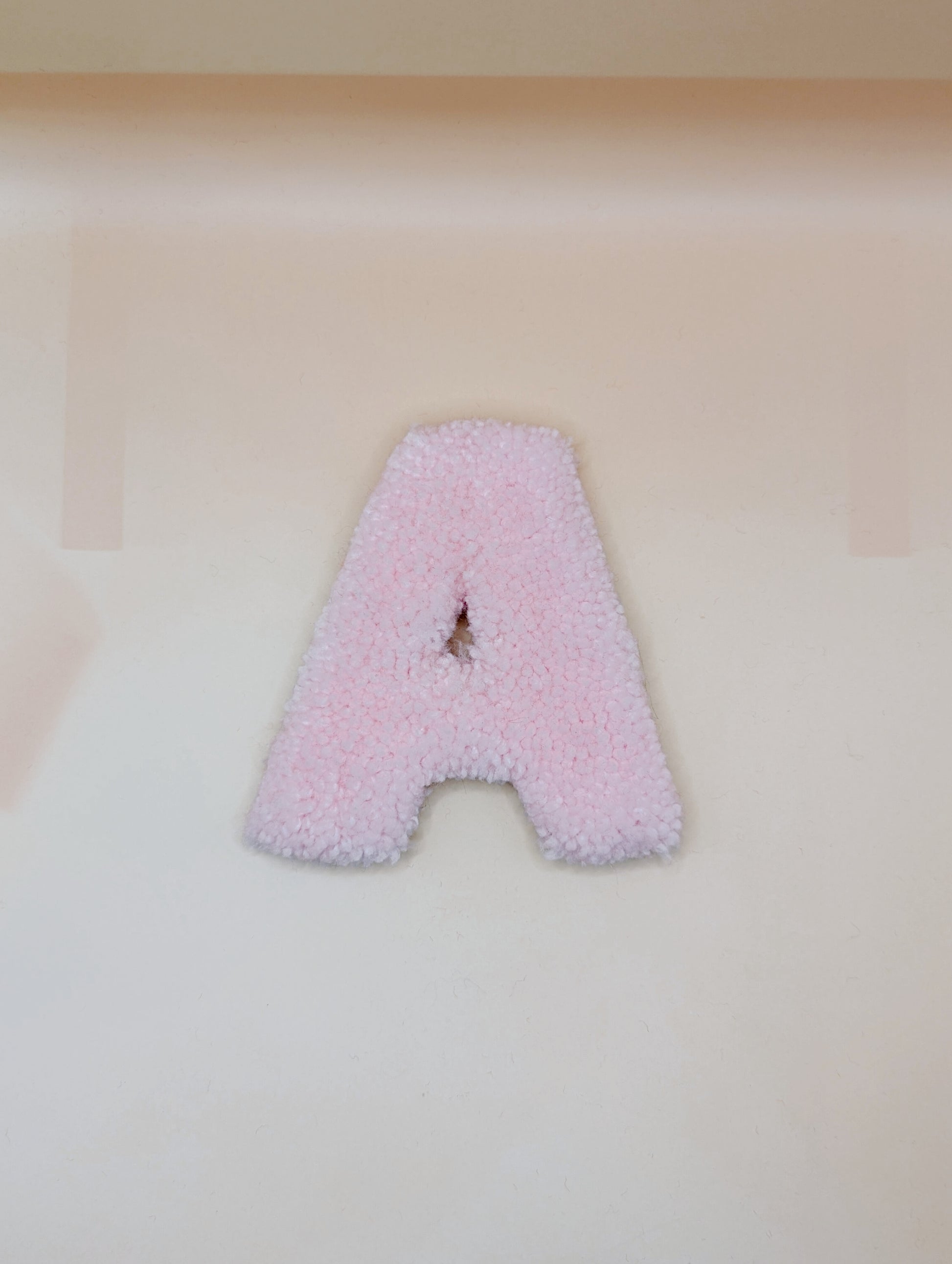 Soft tufted pink letter A with metal hook for easy hanging