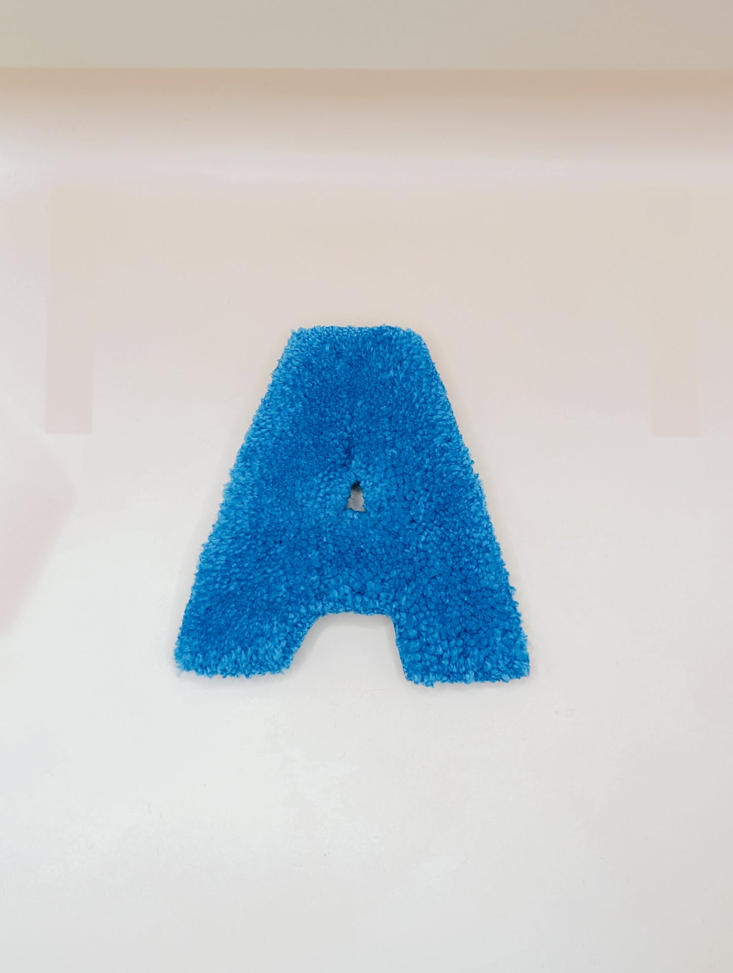 Soft tufted blue letter A with metal hook for easy hanging