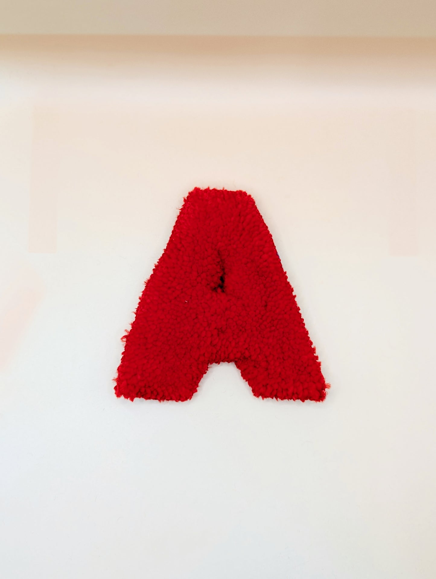 Soft tufted red letter A with metal hook for easy hanging