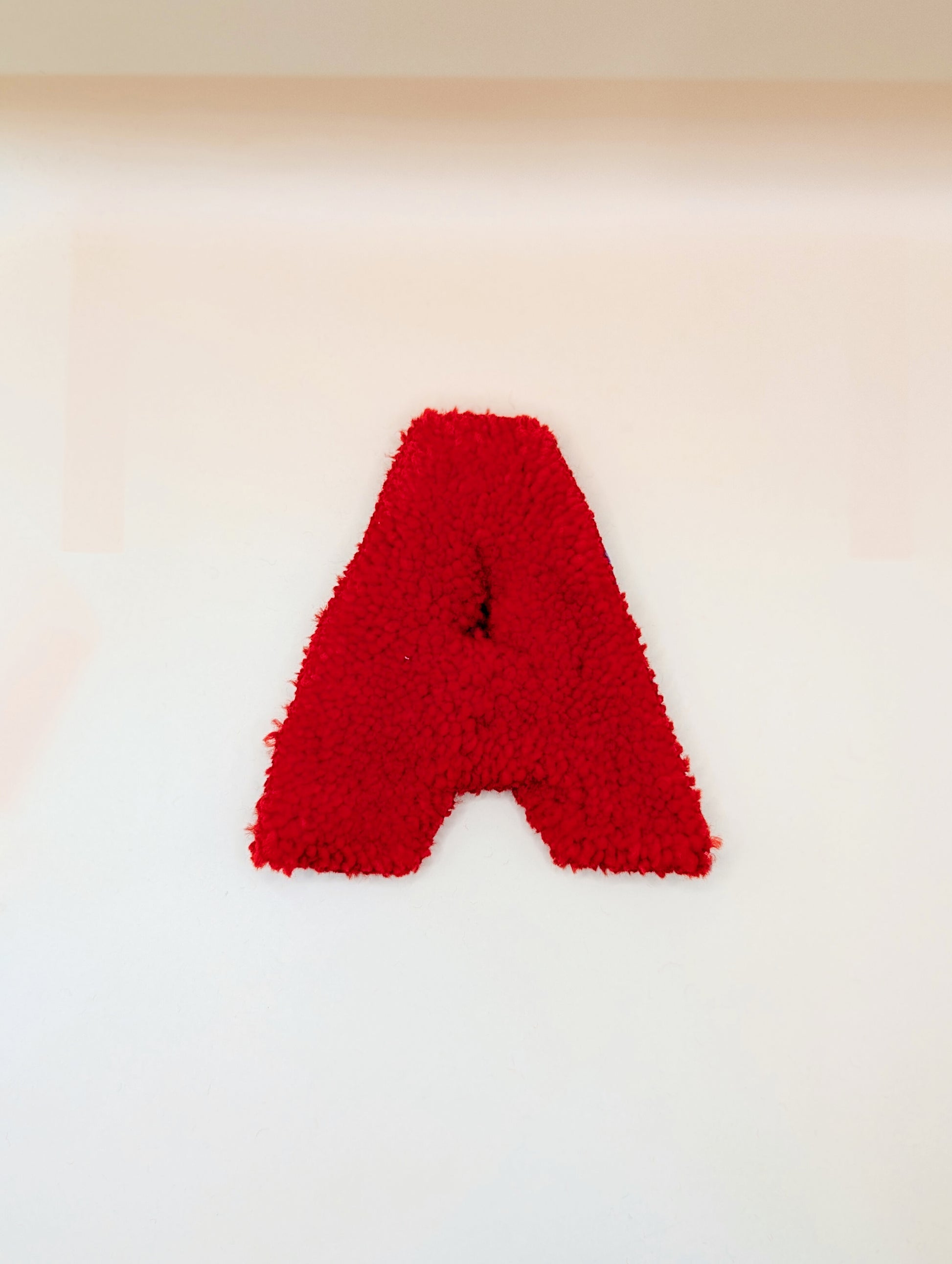 Soft tufted red letter A with metal hook for easy hanging