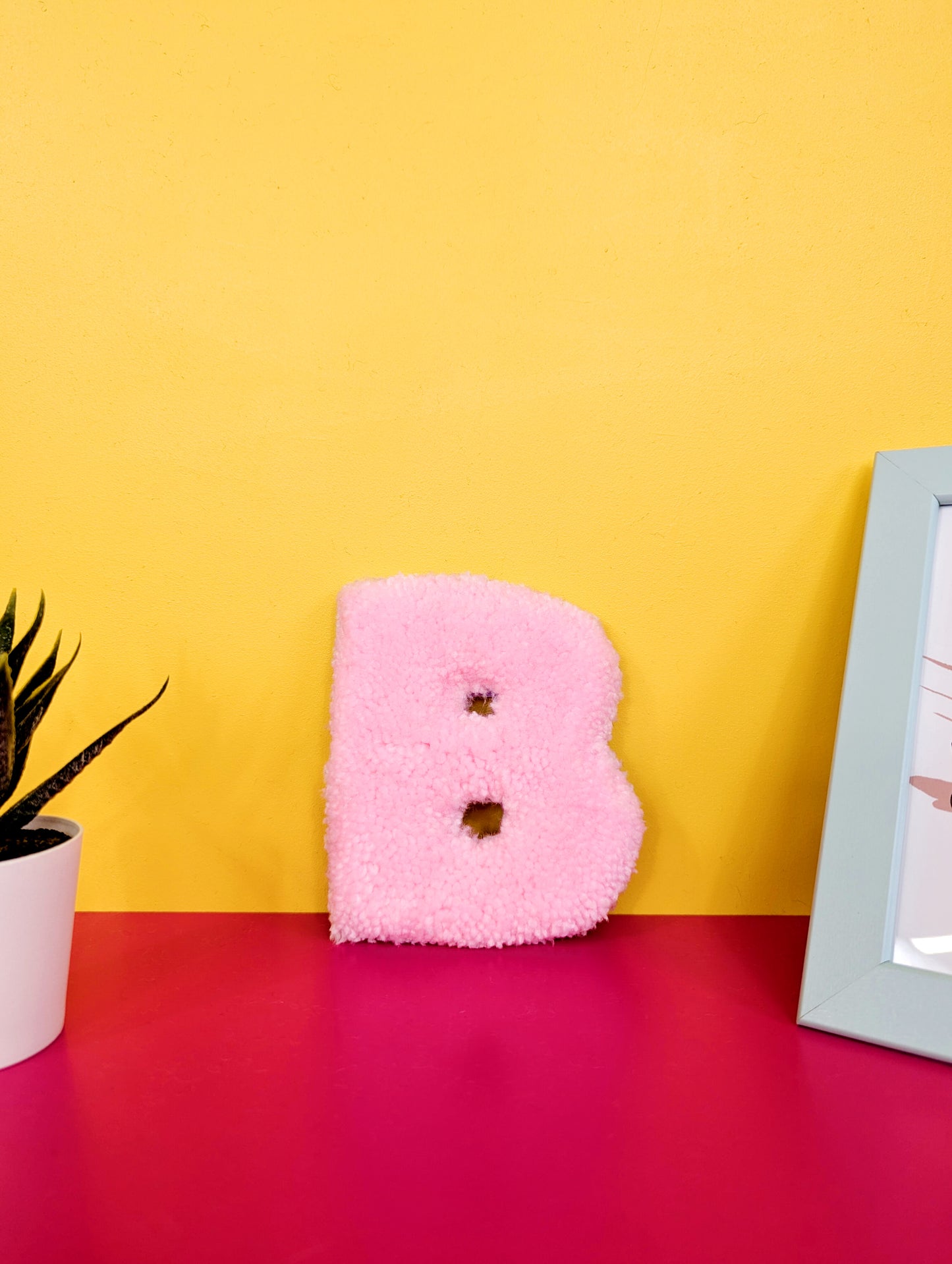 Soft tufted pink letter B with metal hook for easy hanging