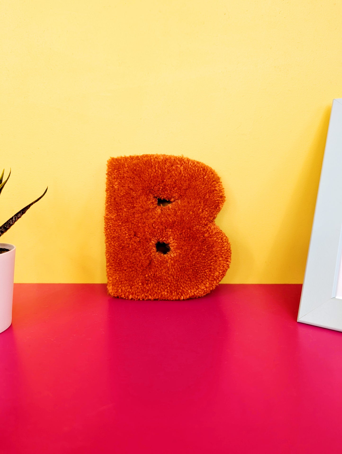 Soft tufted orange letter B with metal hook for easy hanging