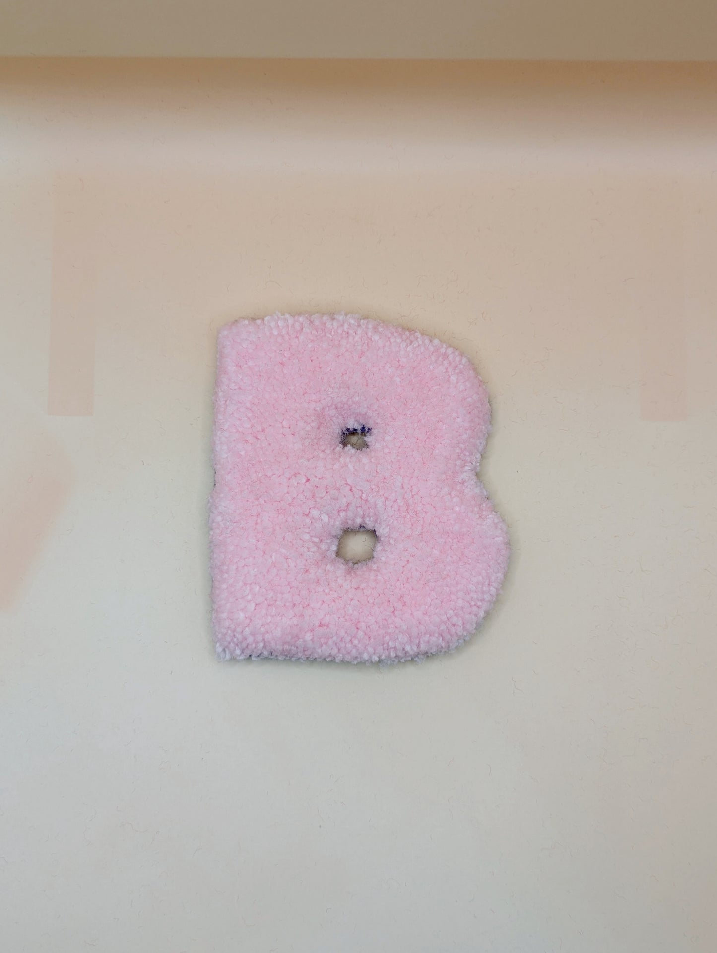 Soft tufted pink letter B with metal hook for easy hanging