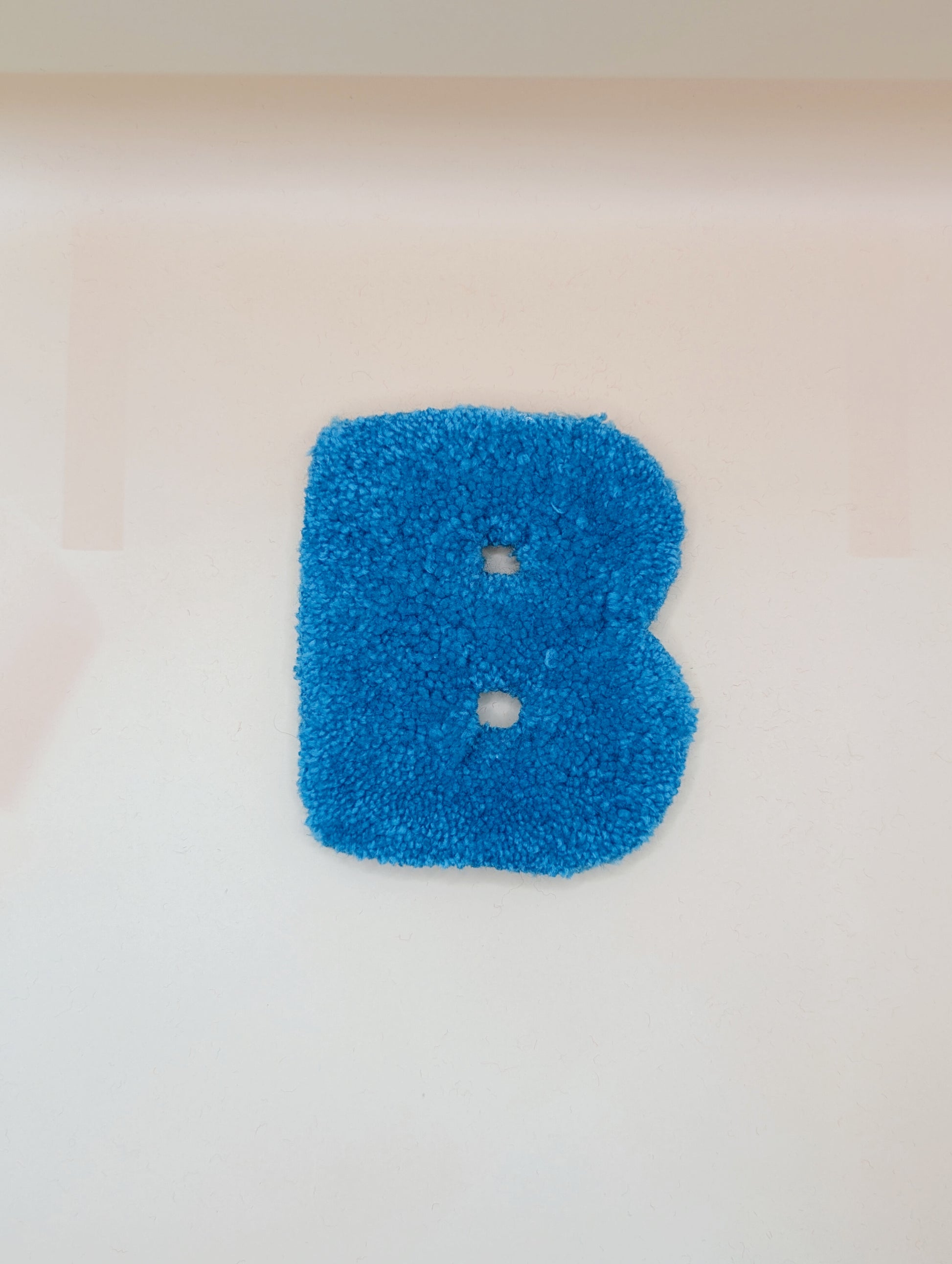 Soft tufted blue letter B with metal hook for easy hanging
