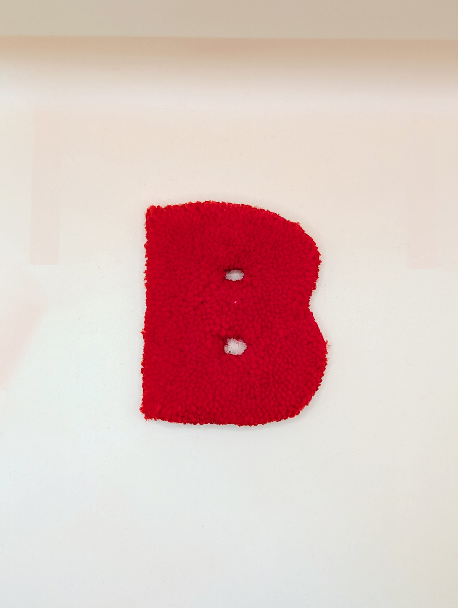 Soft tufted red letter B with metal hook for easy hanging