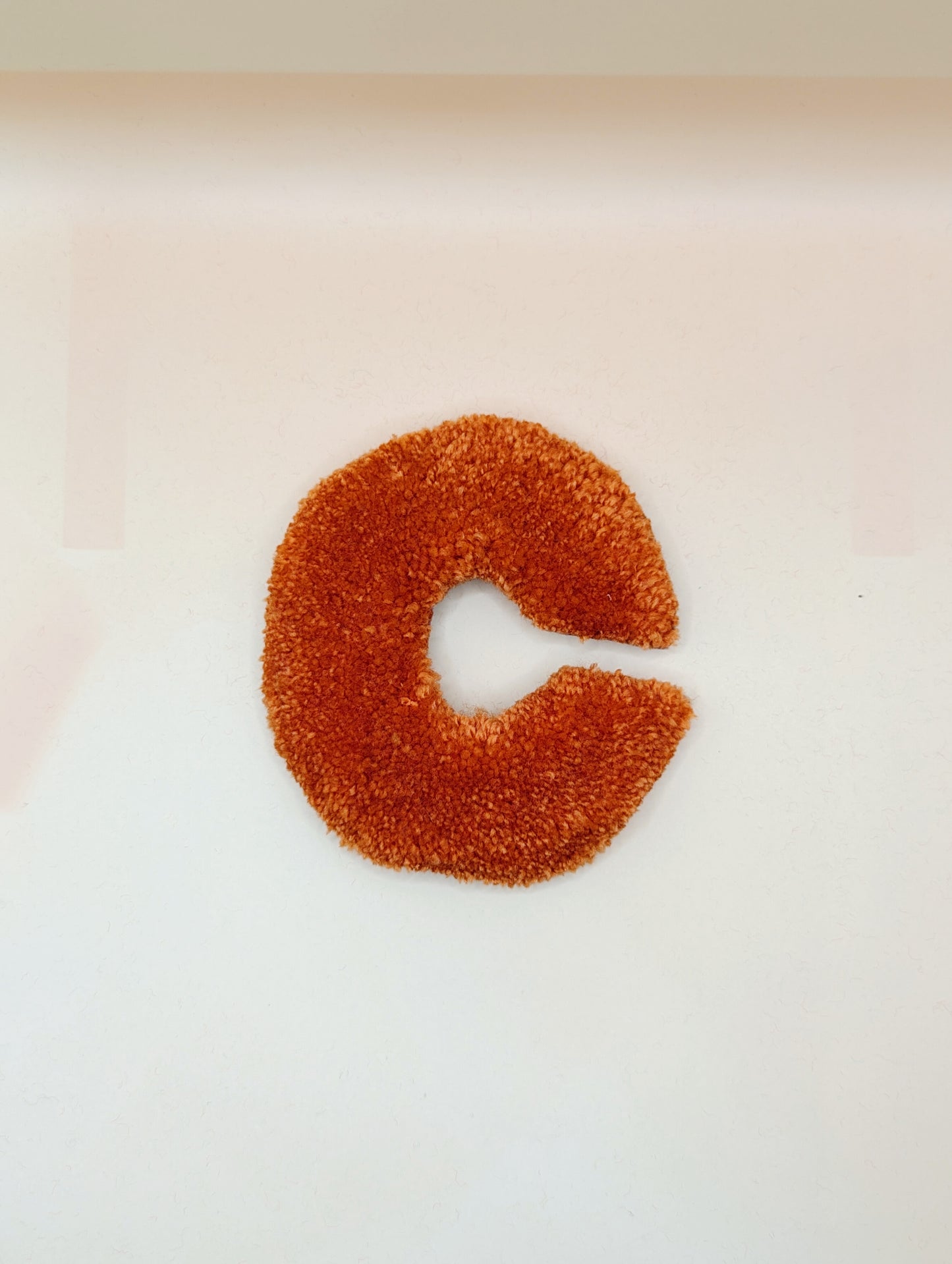 Soft tufted orange letter C with metal hook for easy hanging