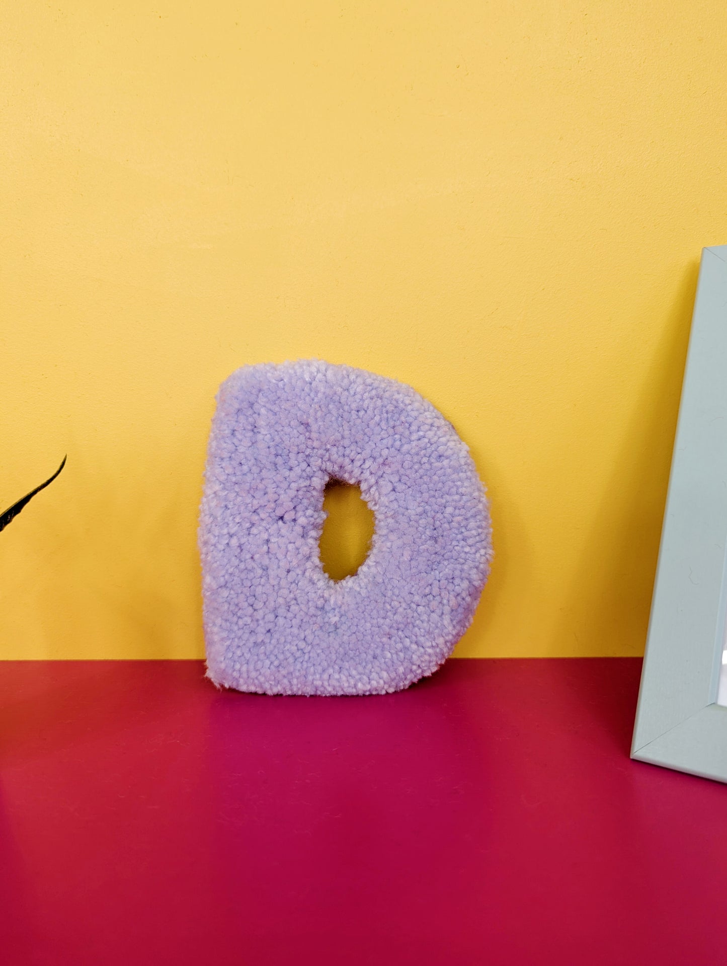 Soft tufted purple letter D with metal hook for easy hanging