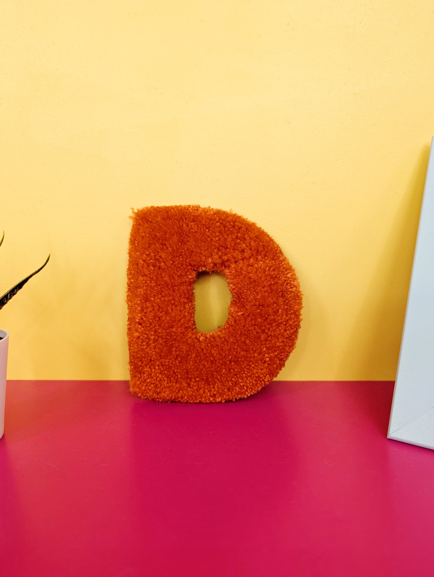 Soft tufted orange letter D with metal hook for easy hanging