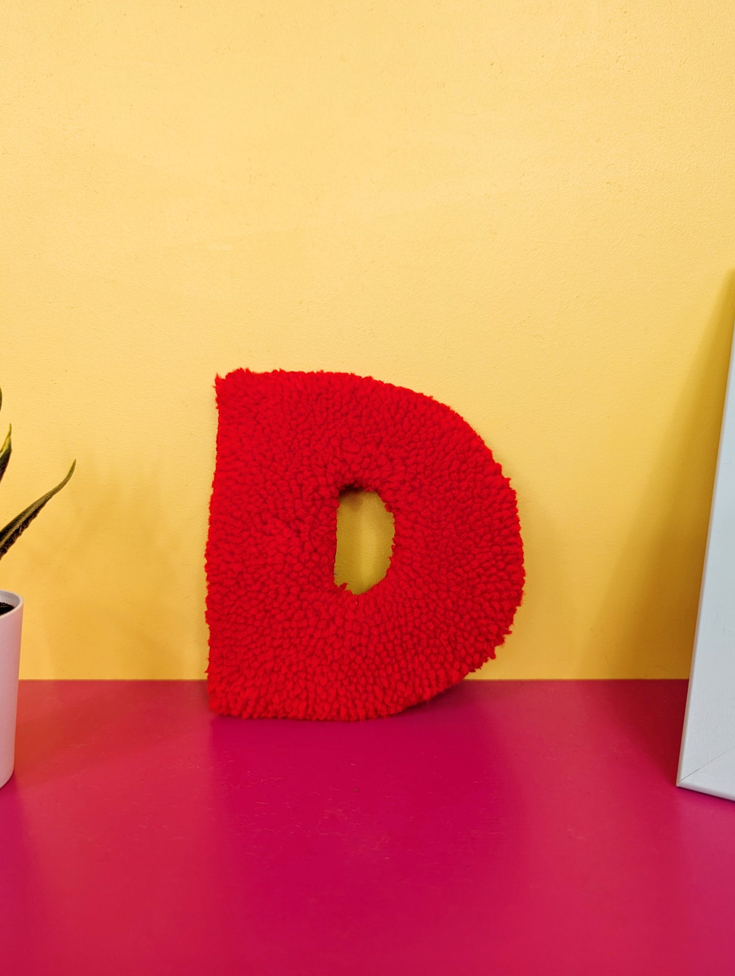 Soft tufted red letter D with metal hook for easy hanging