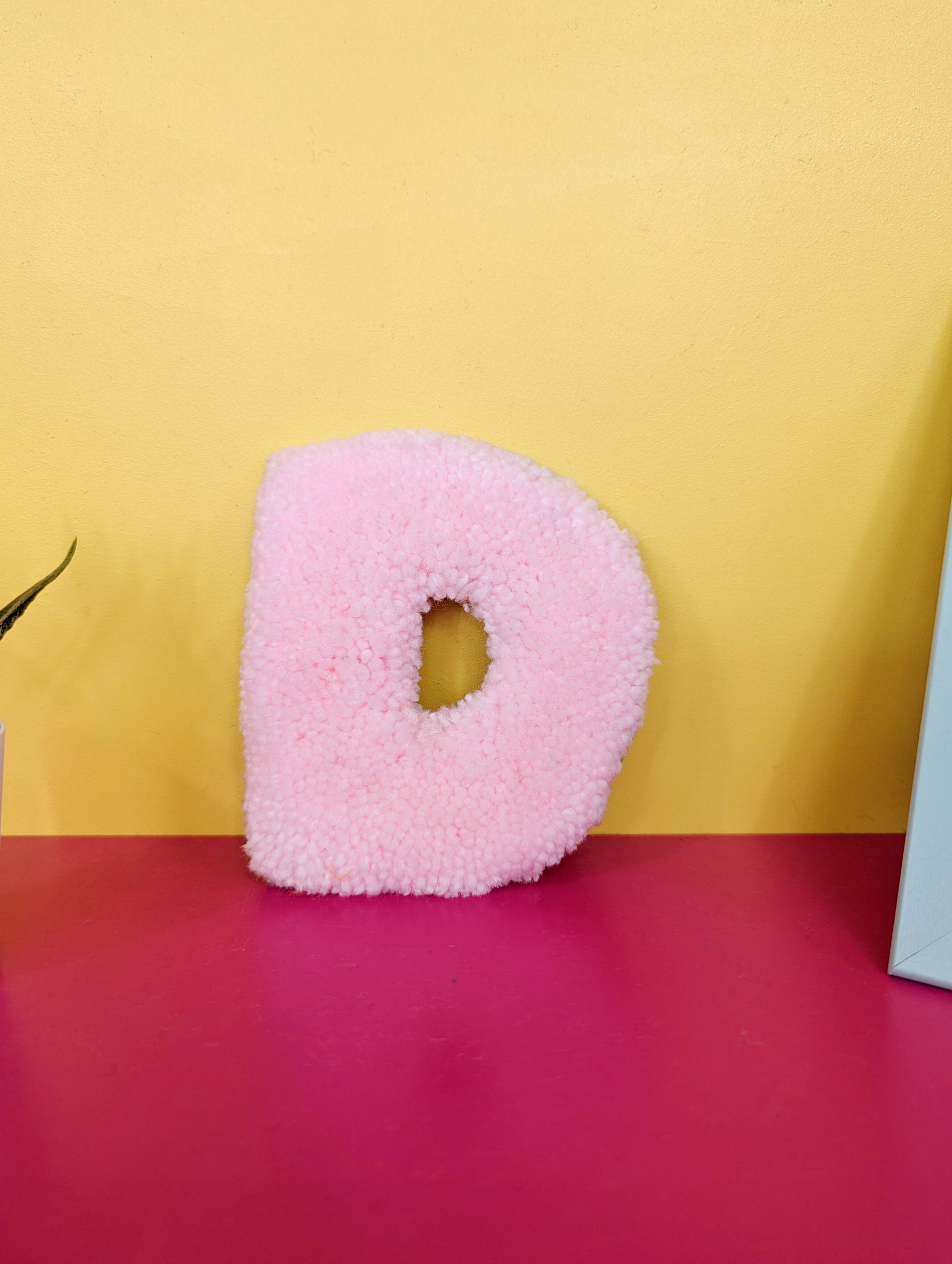 Soft tufted pink letter D with metal hook for easy hanging