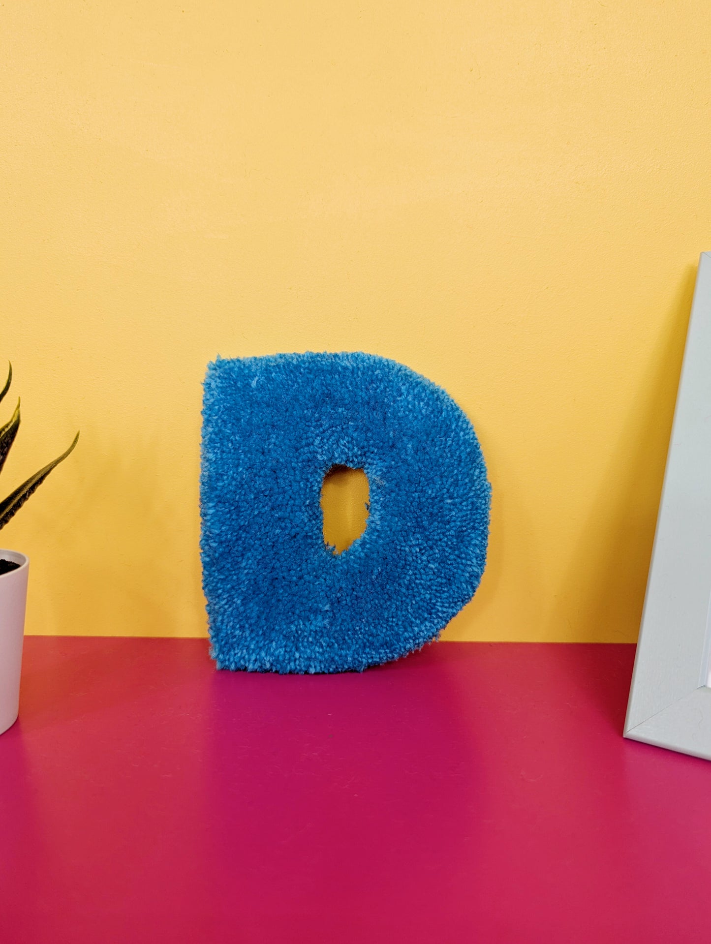 Soft tufted blue letter D with metal hook for easy hanging