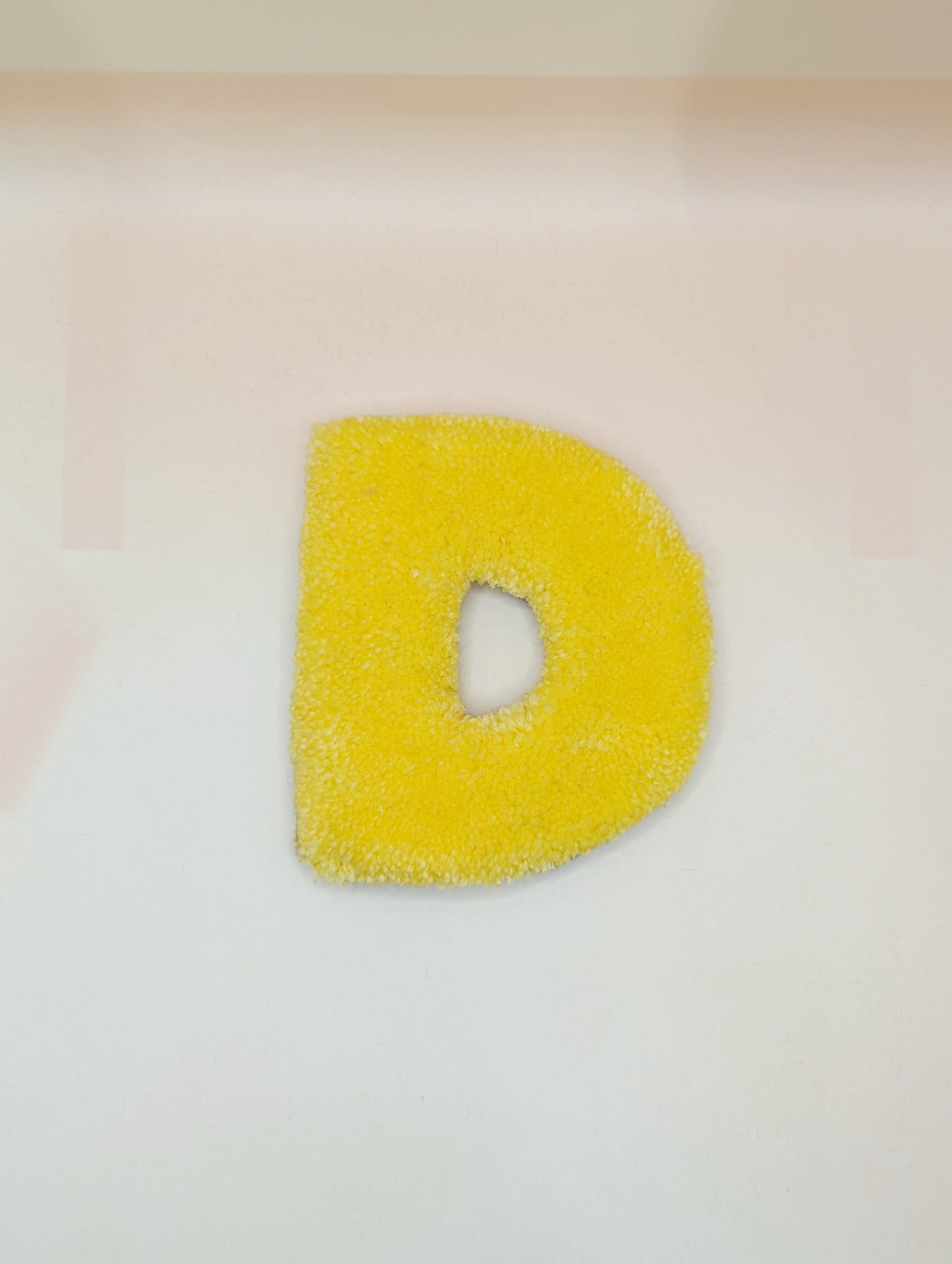Soft tufted yellow letter D with metal hook for easy hanging
