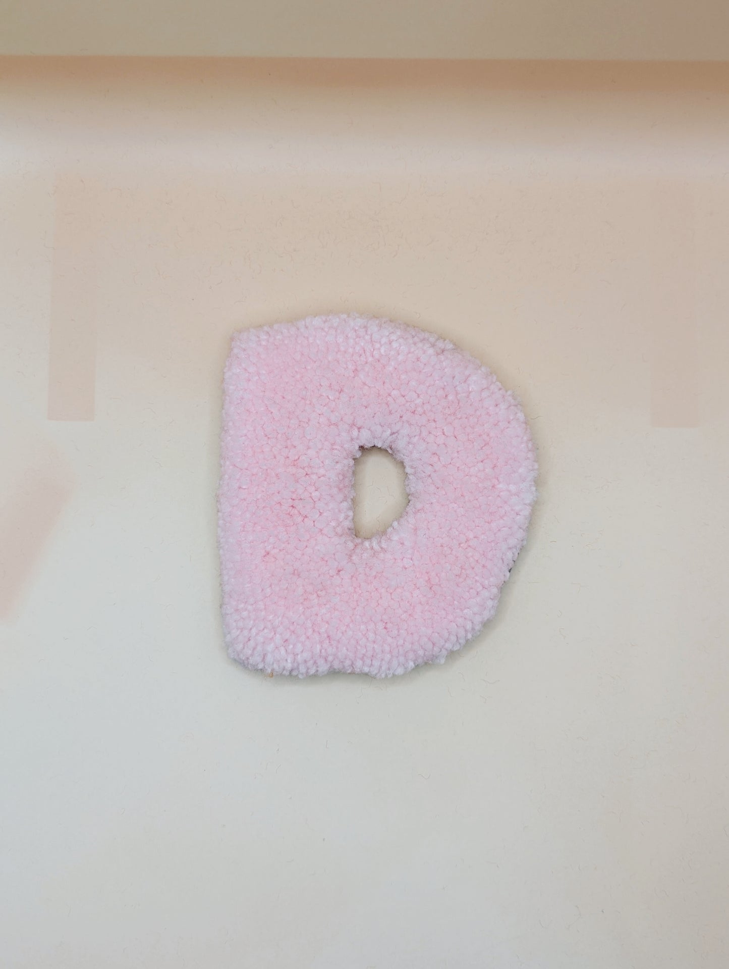 Soft tufted pink letter D with metal hook for easy hanging