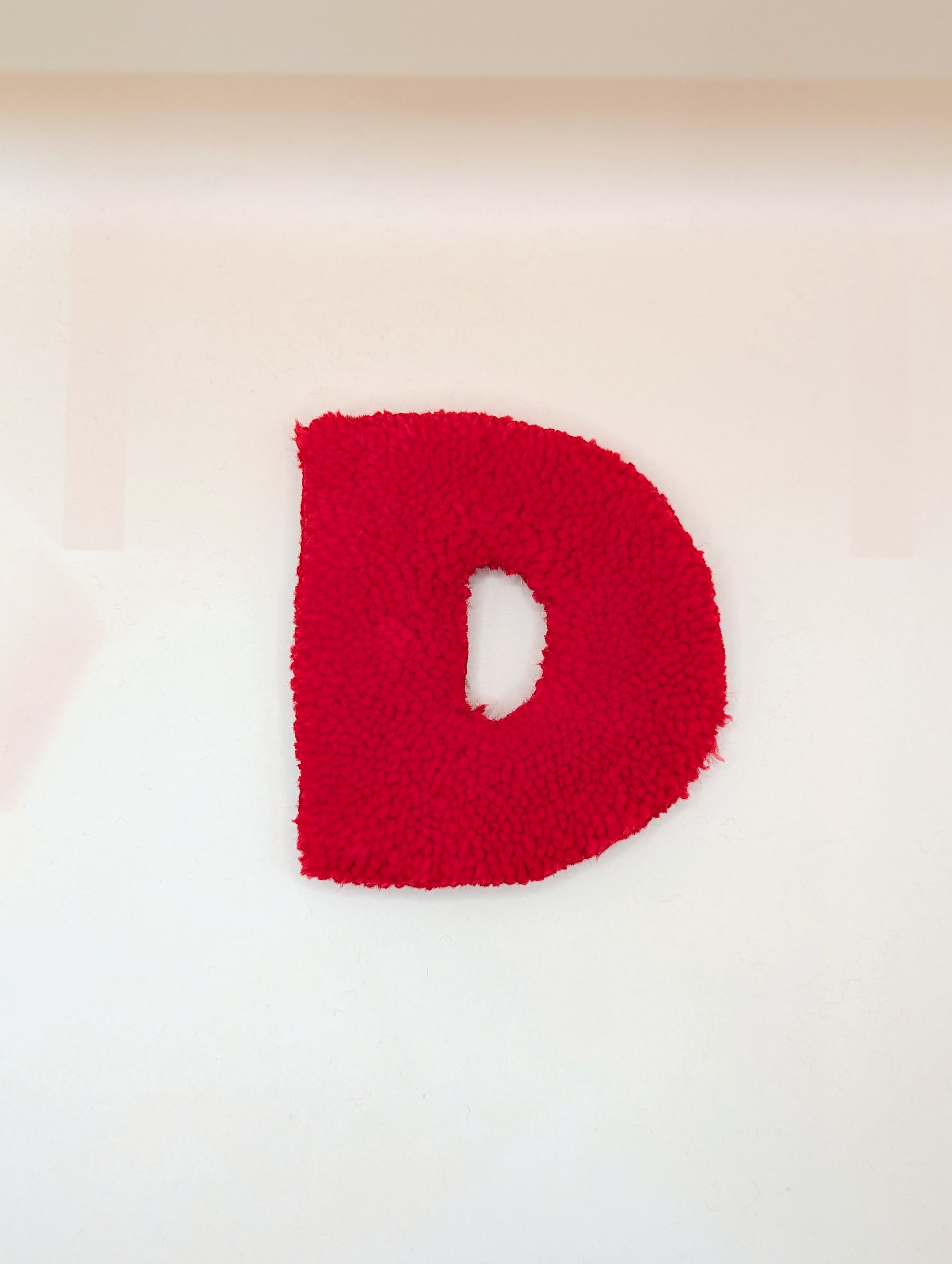 Soft tufted red letter D with metal hook for easy hanging