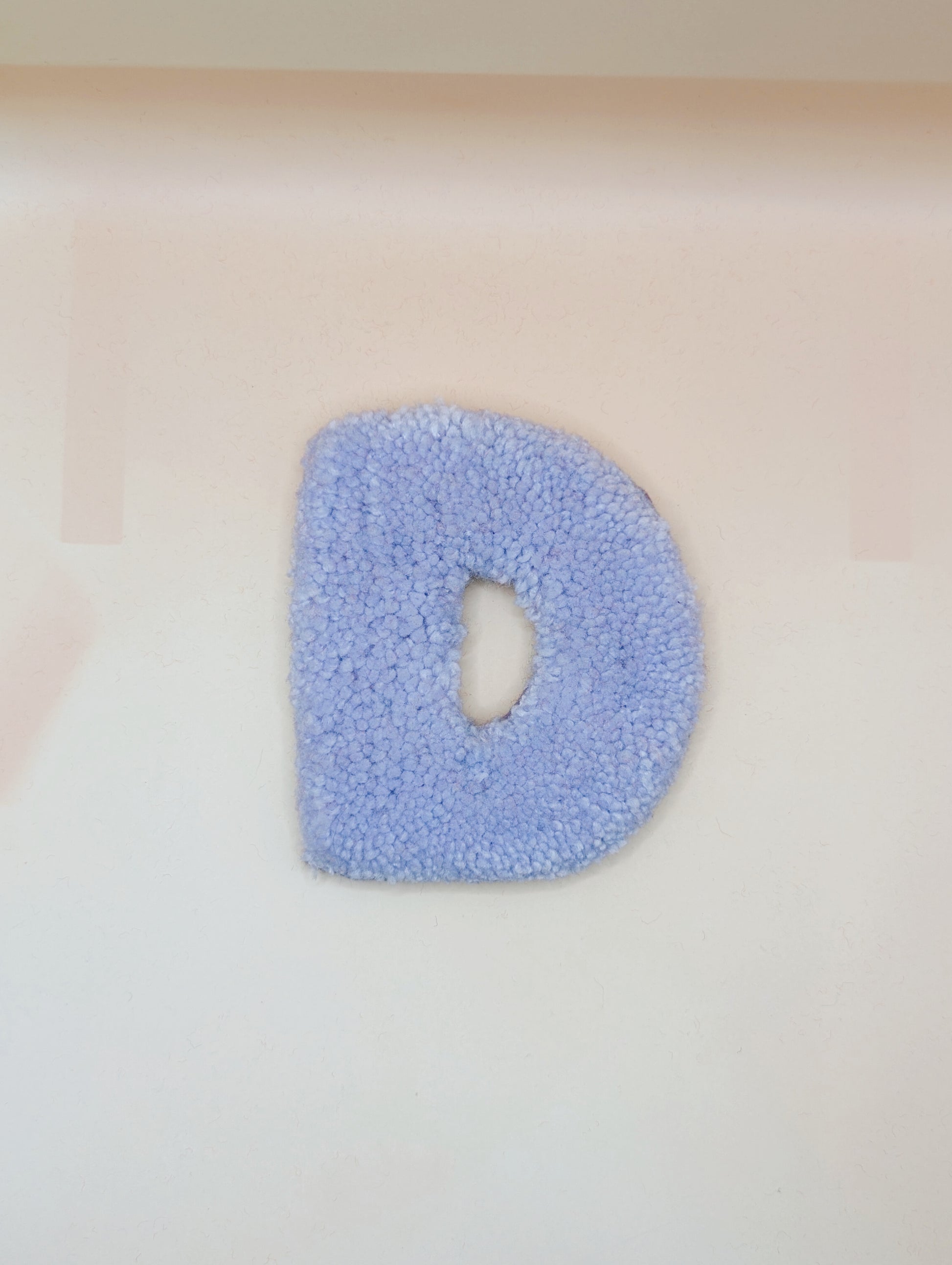 Soft tufted purple letter D with metal hook for easy hanging