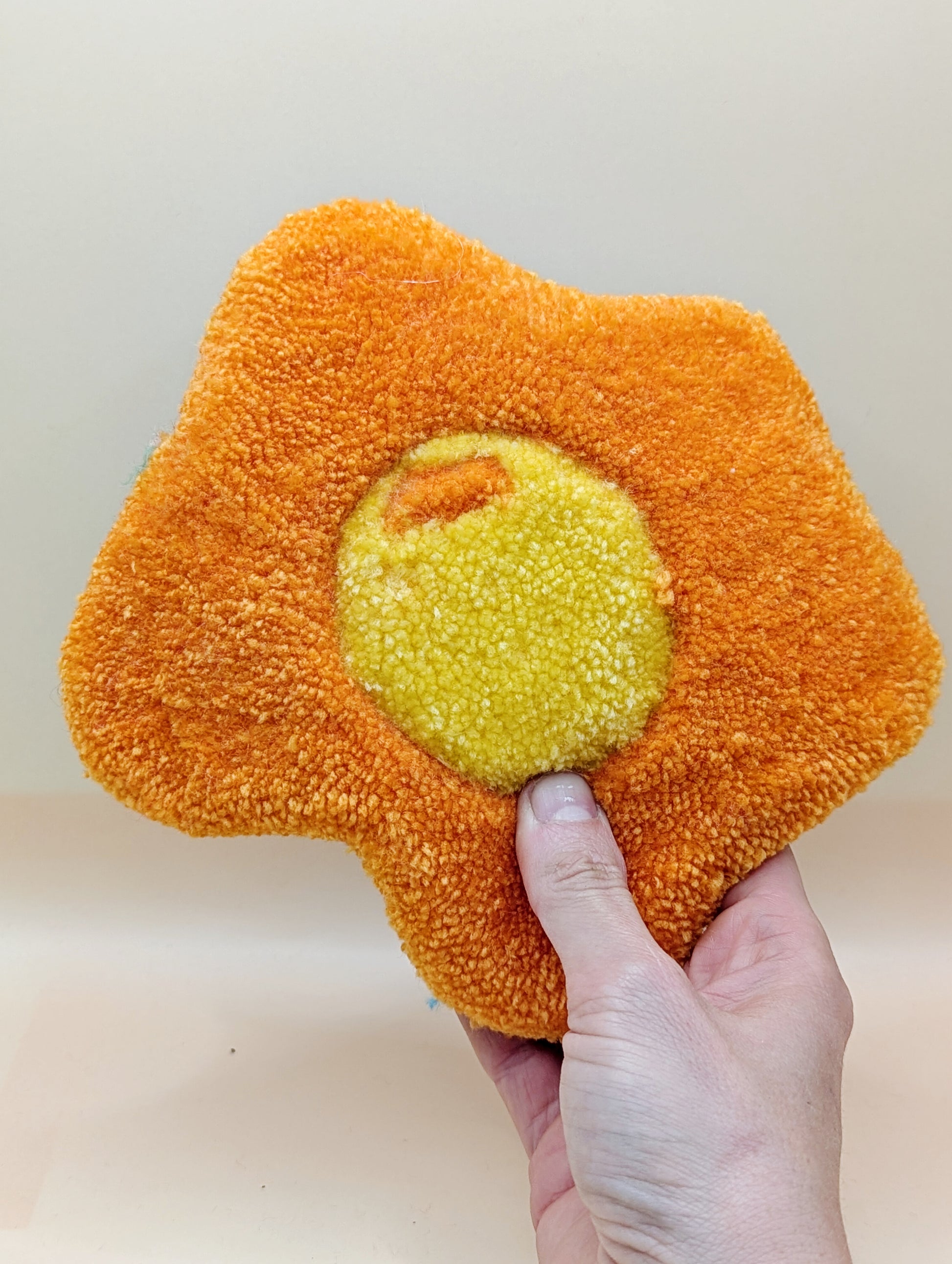 Soft tufted orange and yellow fried egg shaped mini rug/coaster 
