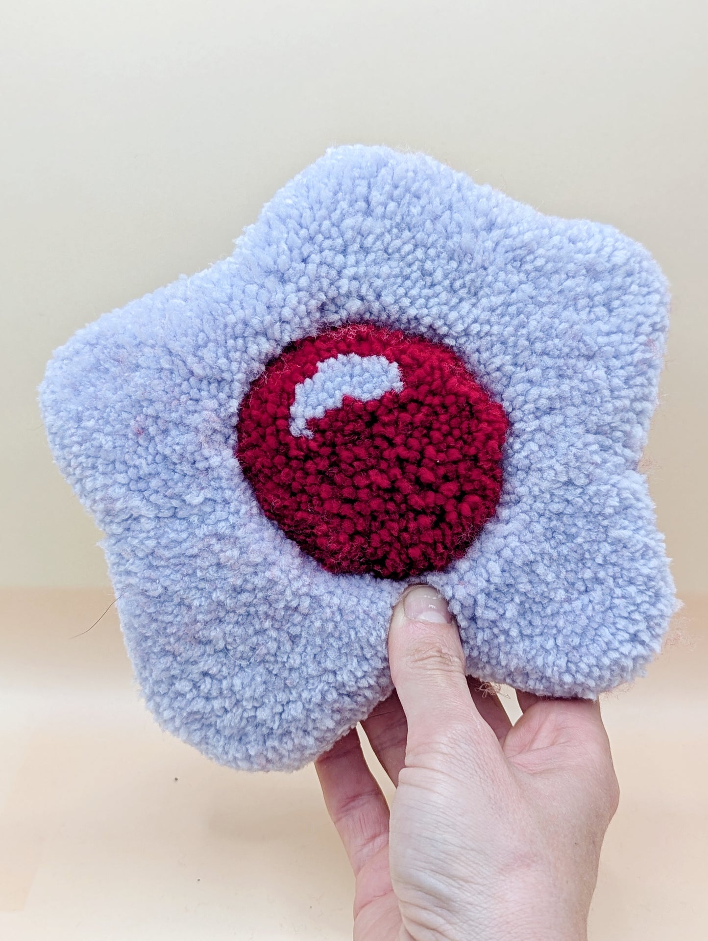 Soft tufted purple and red fried egg shaped mini rug/coaster 