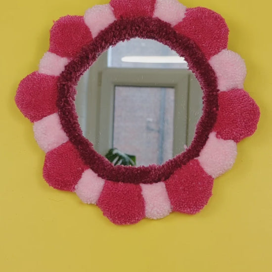 Handmade tufted petal mirror with pink textured yarn petals surrounding a round mirror