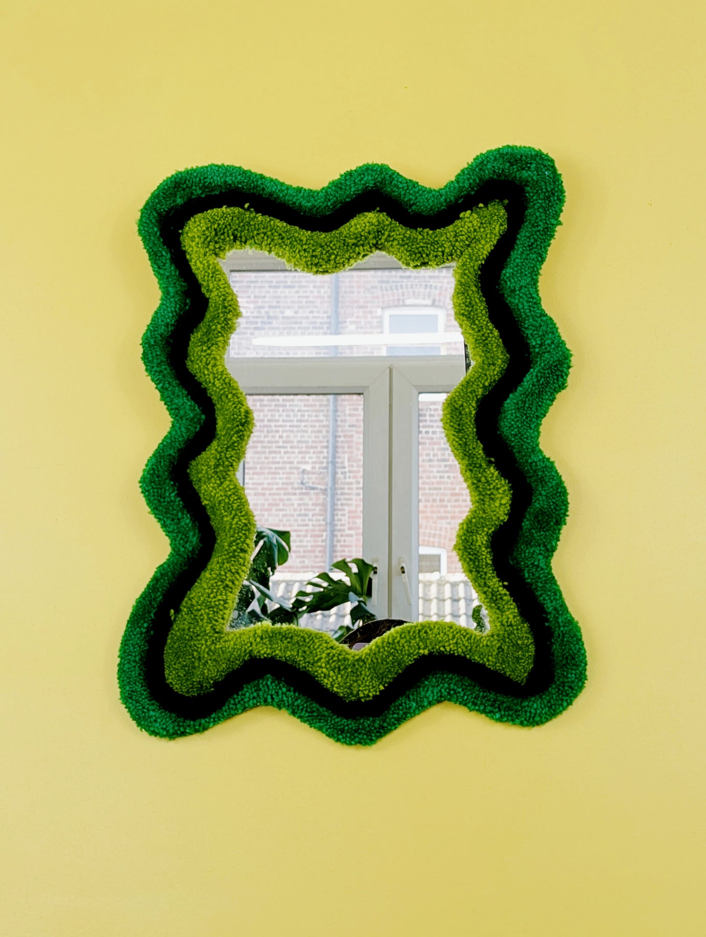 Handmade wavy tufted mirror with colourful textured frame in alternating shades of green, modern aesthetic wall décor for home interiors.