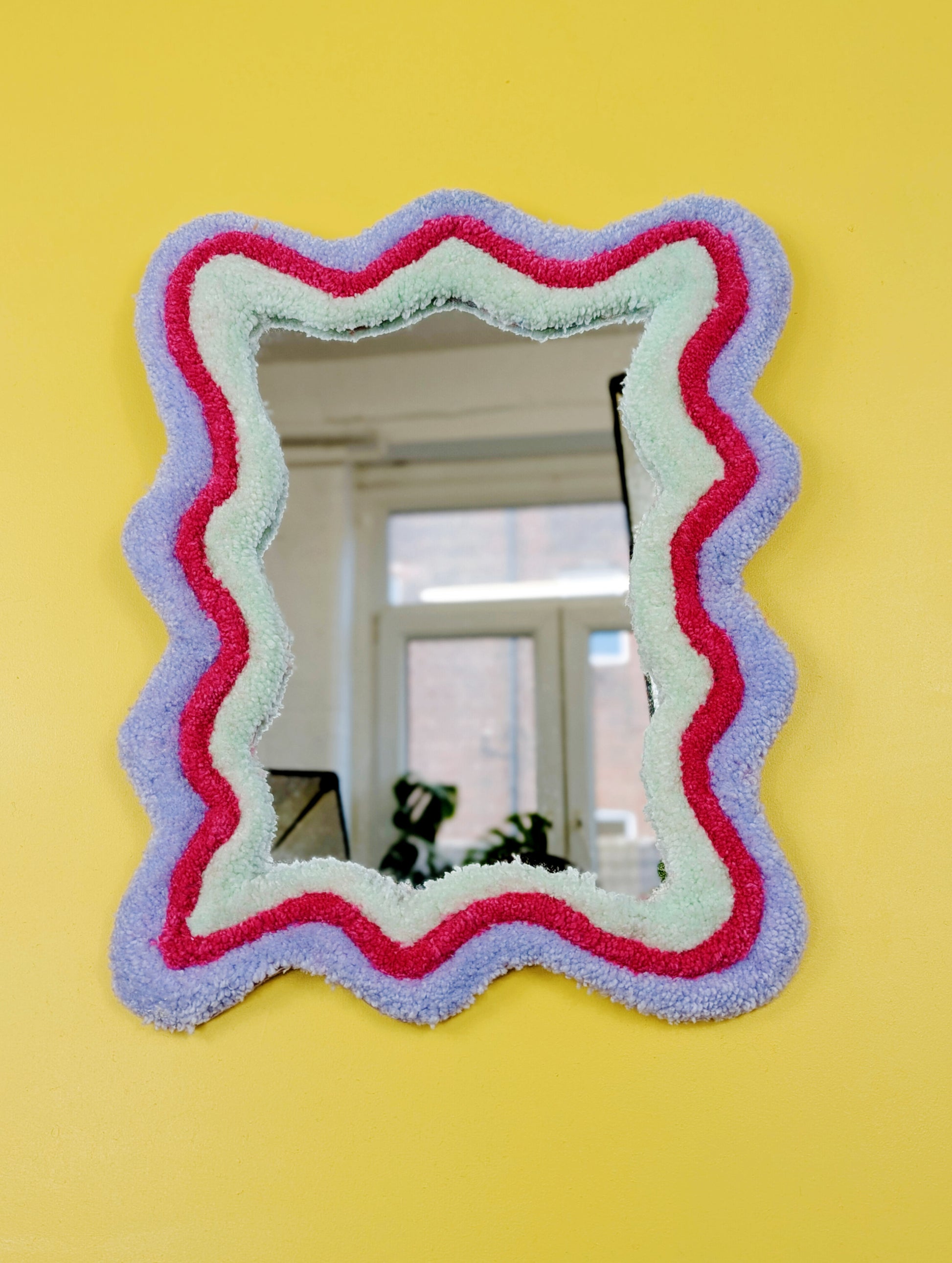 Handmade wavy tufted mirror with colourful textured frame in pastel purple, mint green, and pink, modern aesthetic wall décor for home interiors.
