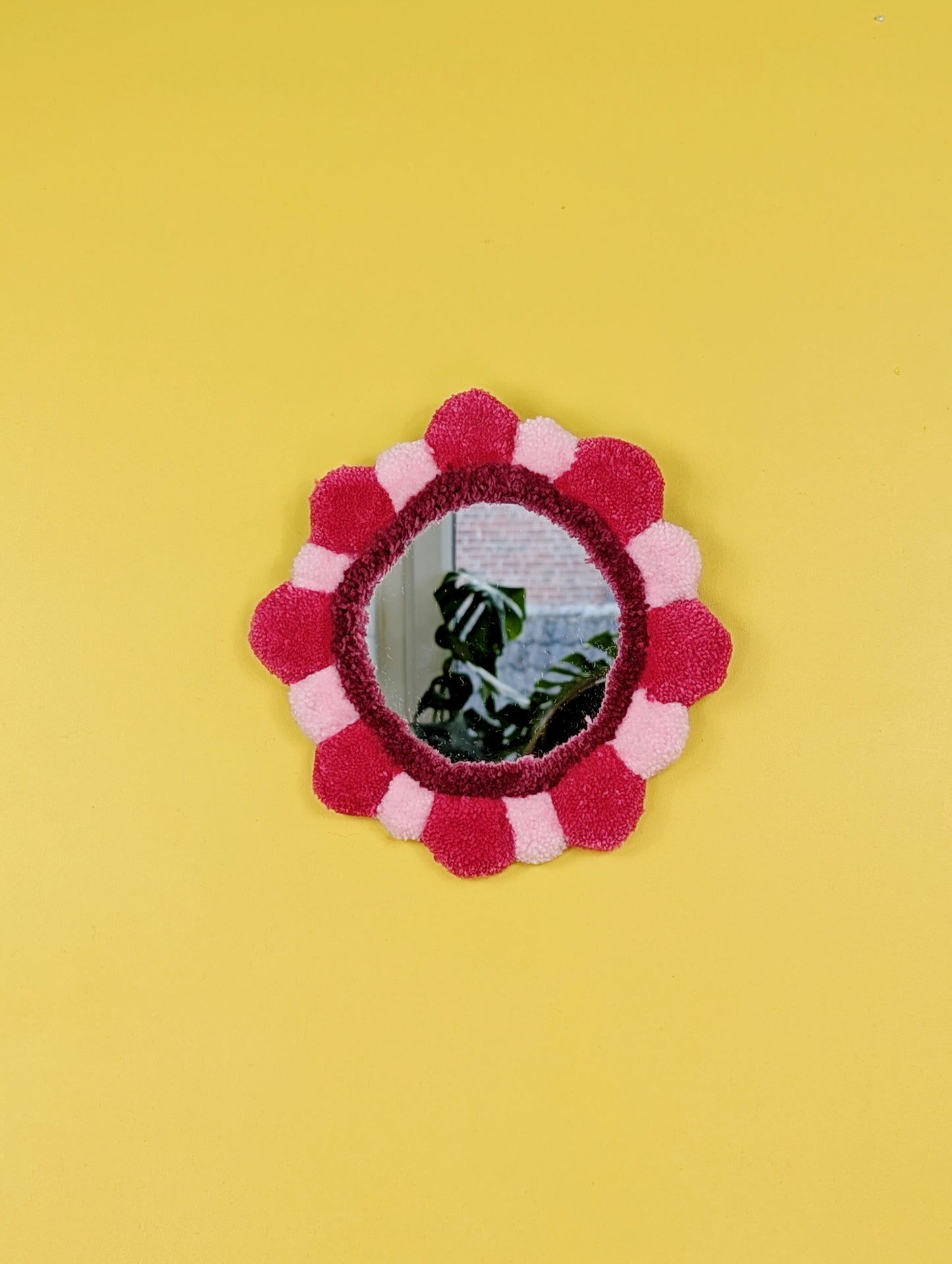 Handmade tufted petal mirror with pink textured yarn petals surrounding a round mirror