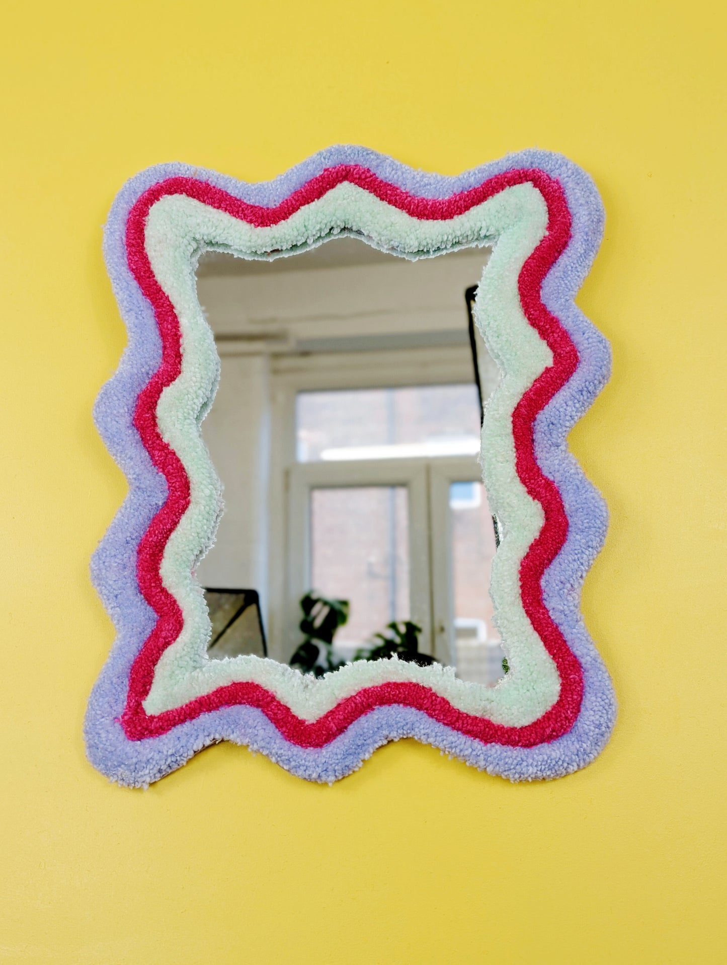 Handmade wavy tufted mirror with colourful textured frame in pastel purple, mint green, and pink, modern aesthetic wall décor for home interiors.