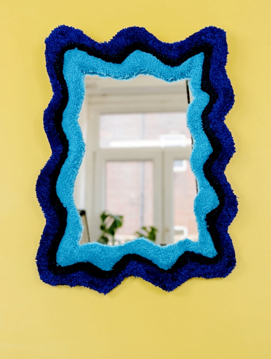 Handmade wavy tufted mirror with colourful textured frame in alternating shades of blue, modern aesthetic wall décor for home interiors.