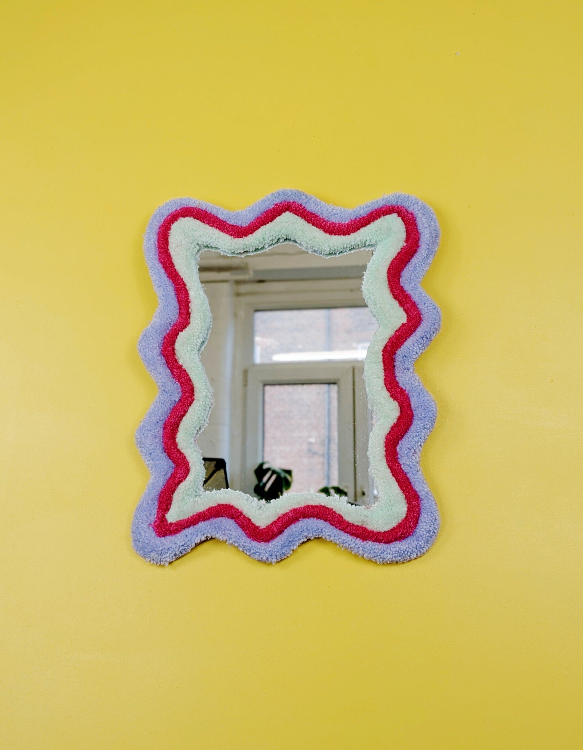 Handmade wavy tufted mirror with colourful textured frame in pastel purple, mint green, and pink, modern aesthetic wall décor for home interiors.