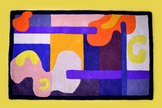 Purple, orange, yellow, cream and burgundy handcrafted tufted wool rug. Abstract shapes and curves. Dark purple border with block colours. Pictured on a yellow background.